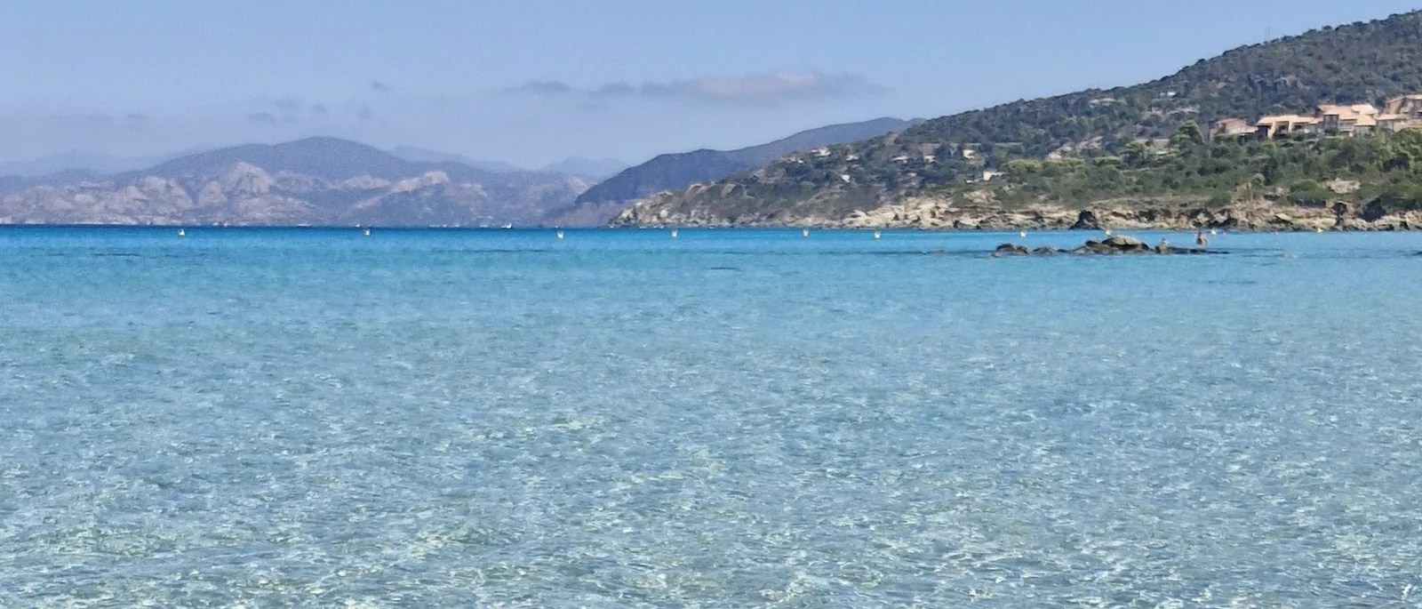 Une baie de Corse à l&rsquo;eau turquoise, les montagnes en arrière-plan