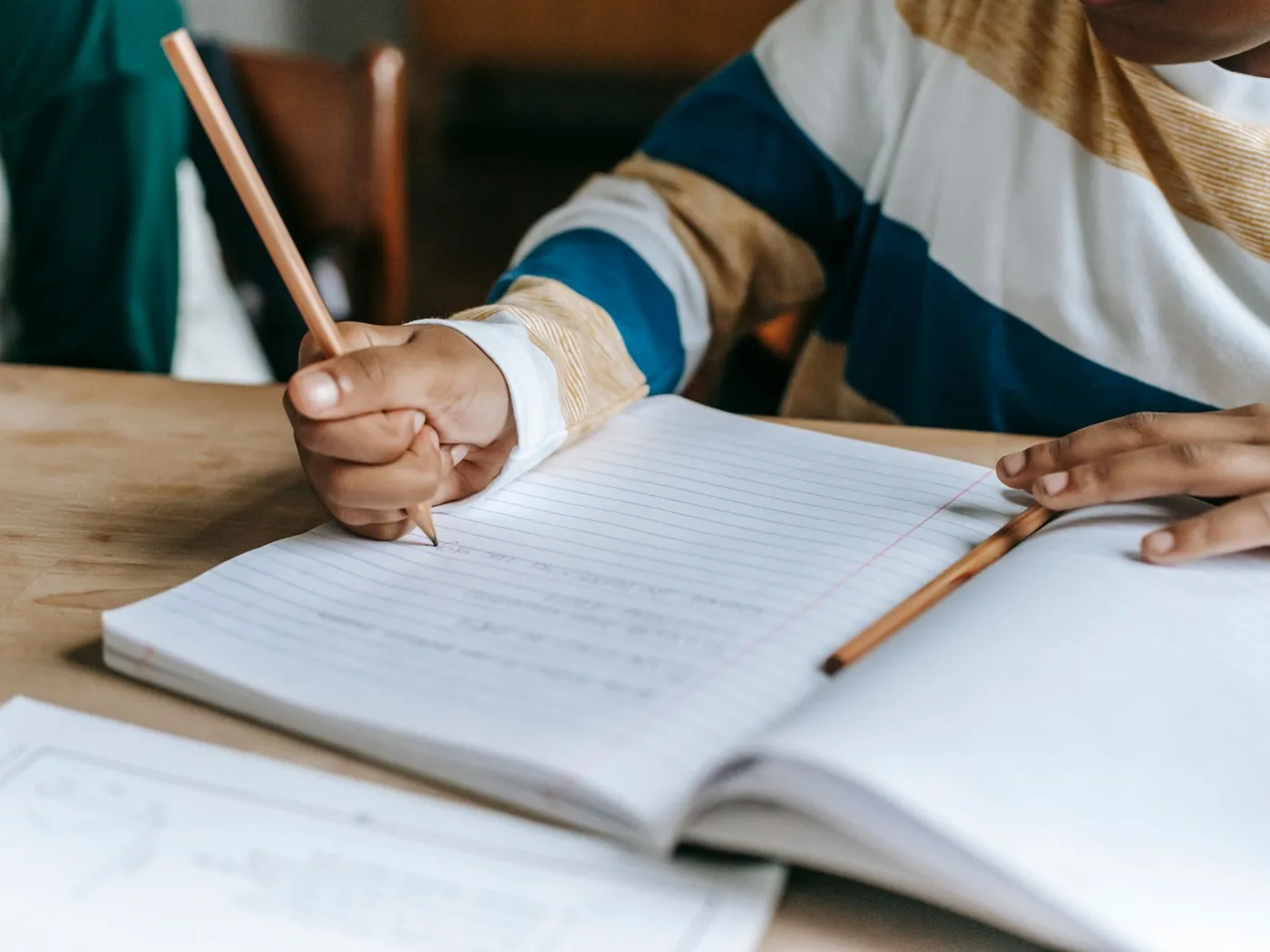 Les mains d'un enfant qui écrit dans son cahier