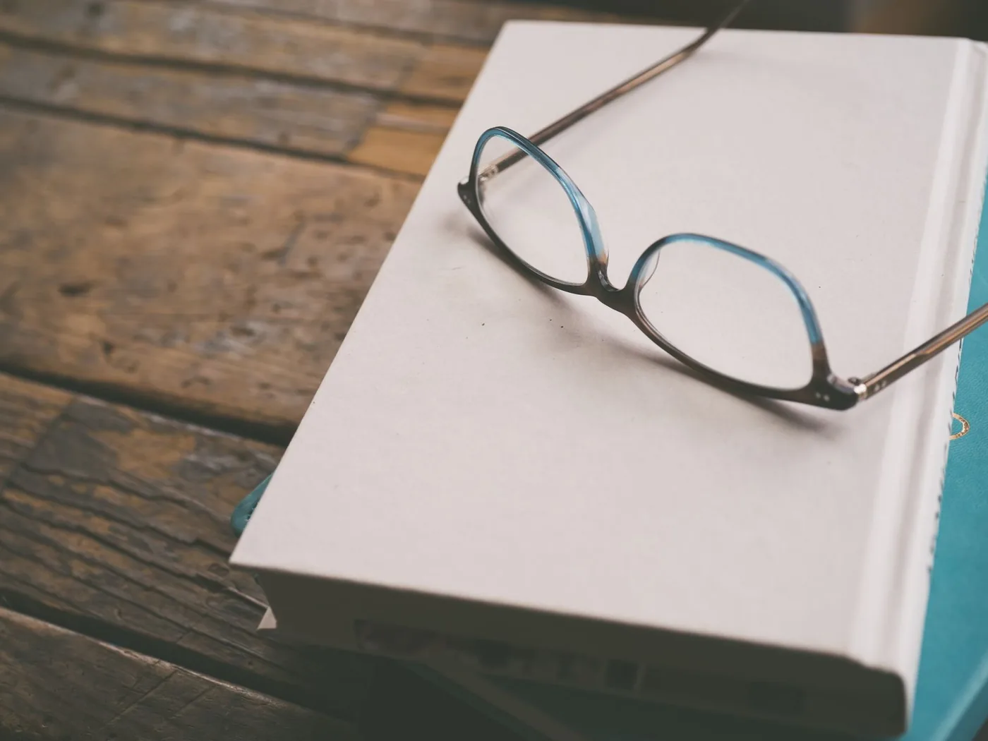 Un livre et des lunettes posés sur une table en bois