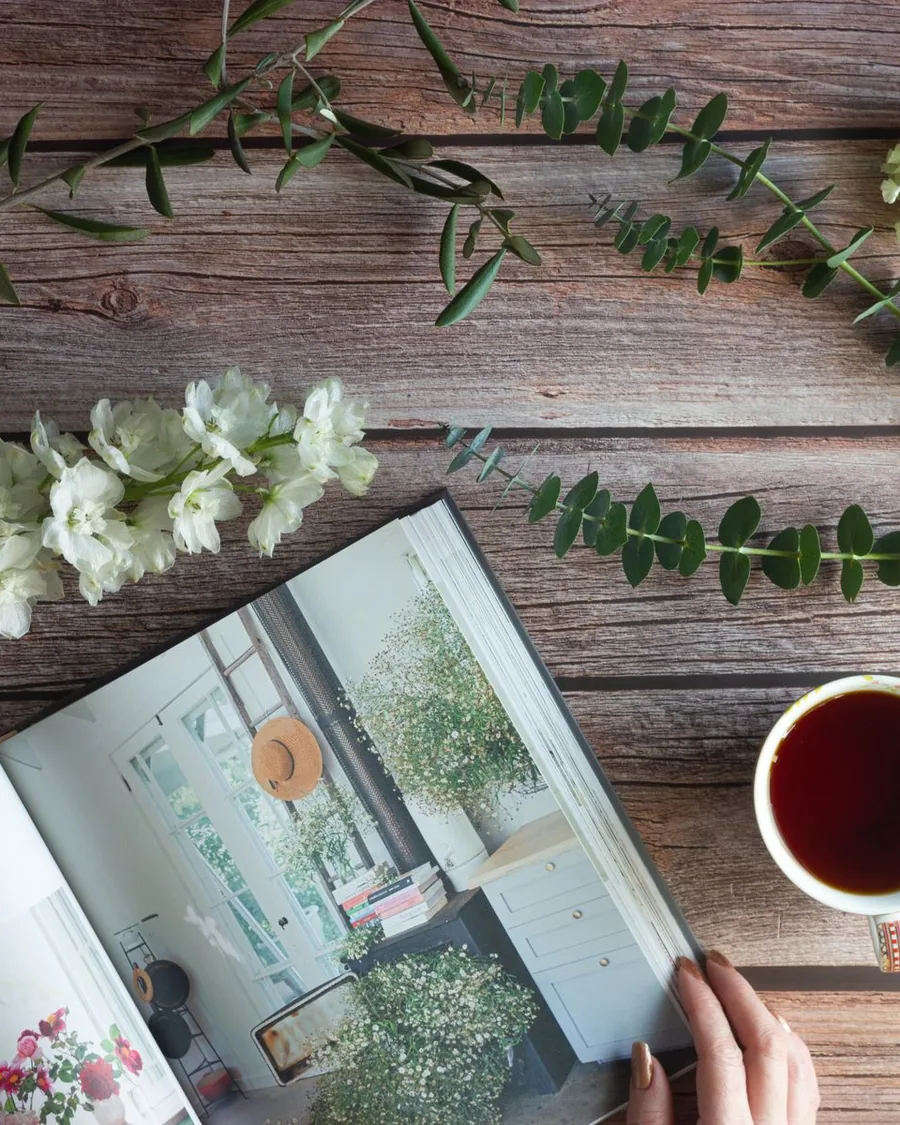 Un livre ouvert, une tasse de thé et des fleurs sur une table en bois